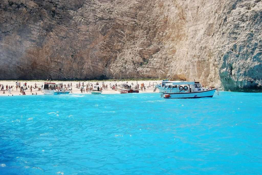 Εικόνα της παραλίας Ναυάγιο στη Ζάκυνθο. Ένα μαγευτικό τοπίο με γαλαζοπράσινα νερά, βραχώδεις αποκρημνίσεις και ένα ναυάγιο πλοίου στην άκρη της παραλίας.